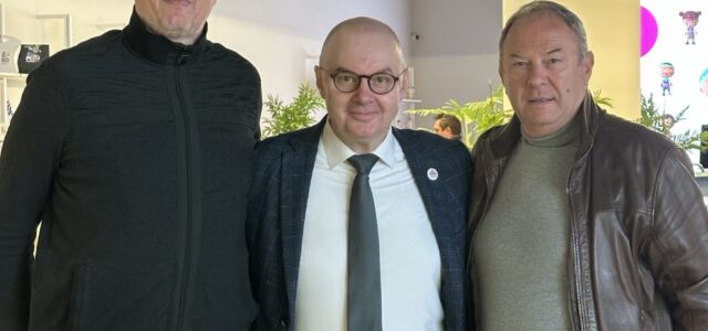 Three men posing indoors together.